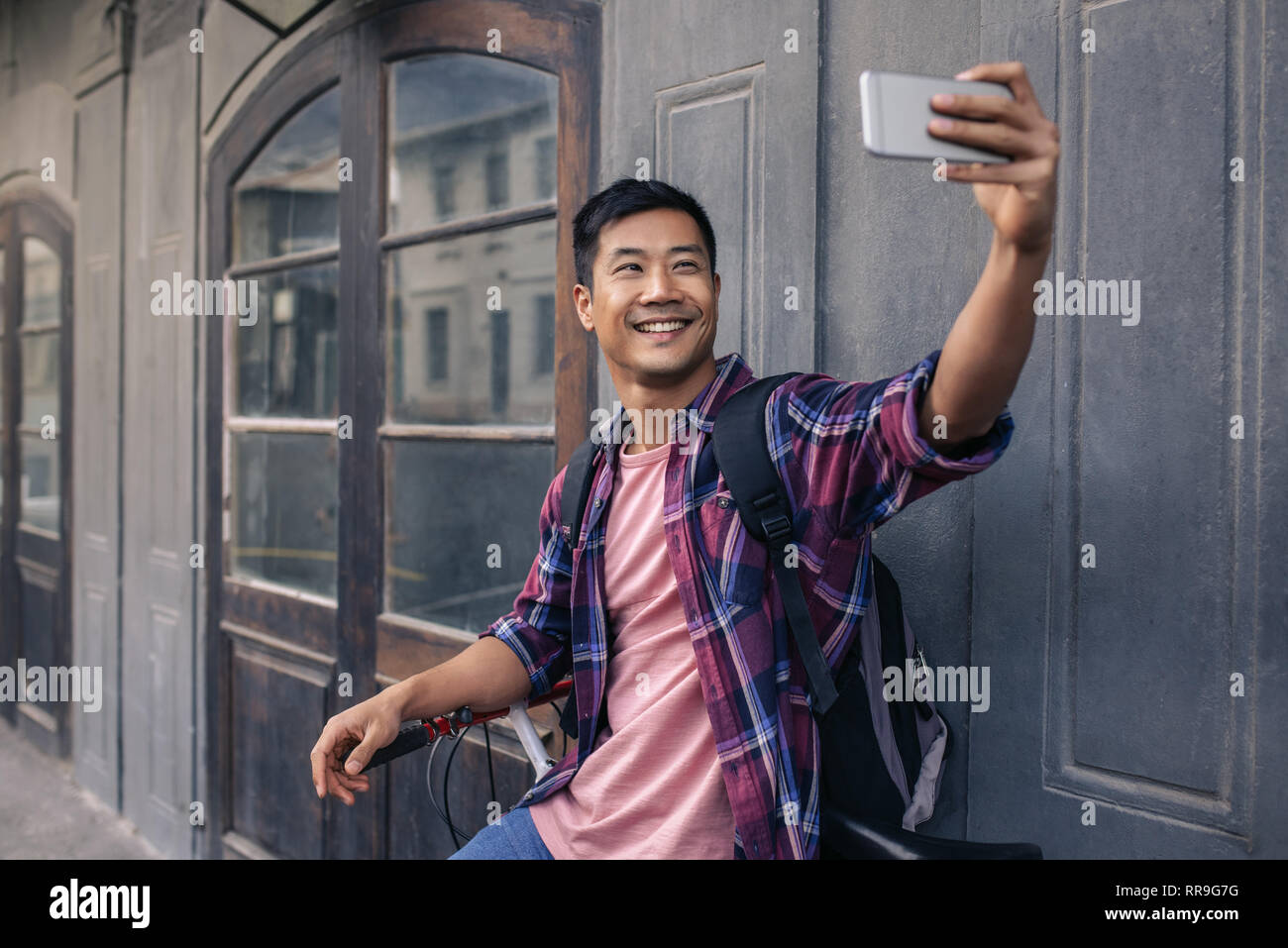 Lächelnden jungen asiatischer Mann einen selfie auf seinem Fahrrad Stockfoto