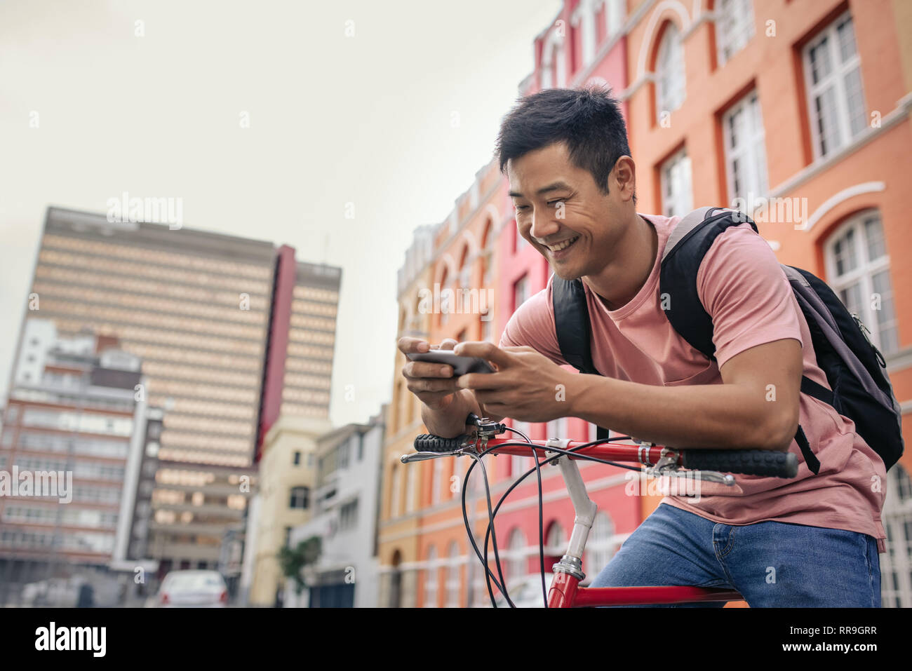 Lächelnden jungen Mann sitzt auf seinem Fahrrad eine sms senden Stockfoto