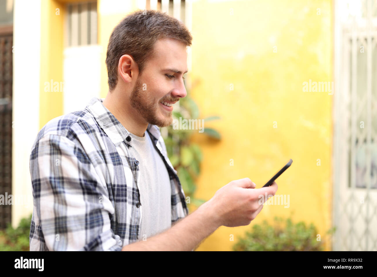 Profil eines Mannes mit Smart Phone im Freien zu Fuß auf der Straße Stockfoto