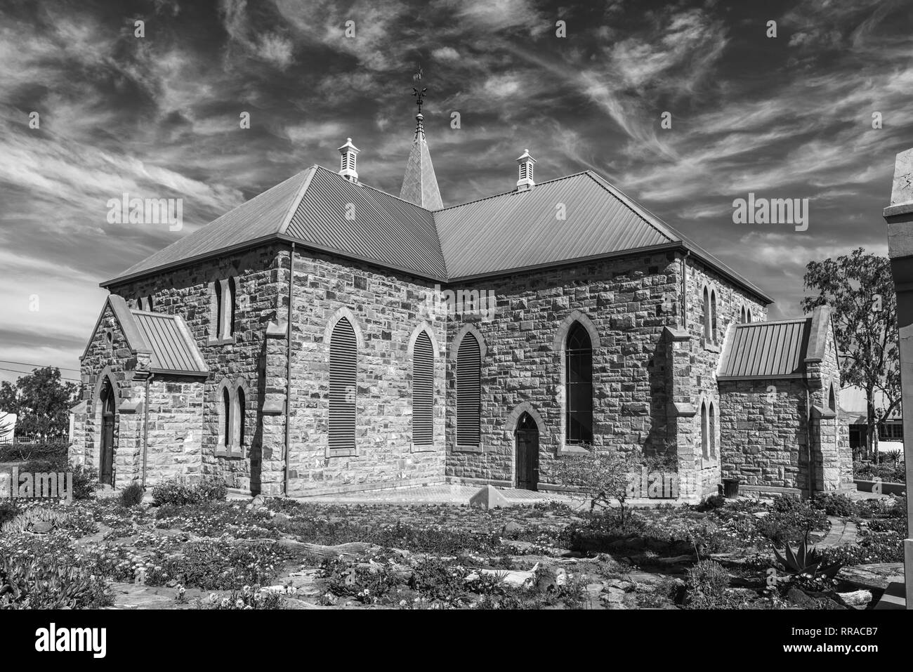 WILLISTON, SÜDAFRIKA, 31. AUGUST 2018: die Niederländische Reformierte Kirche in Williston in der Northern Cape Provinz. Blumen sind sichtbar. Schwarzweiß Stockfoto