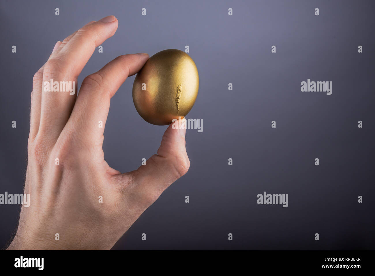 Mann hand Goldene Ei auf grauem Hintergrund Stockfoto