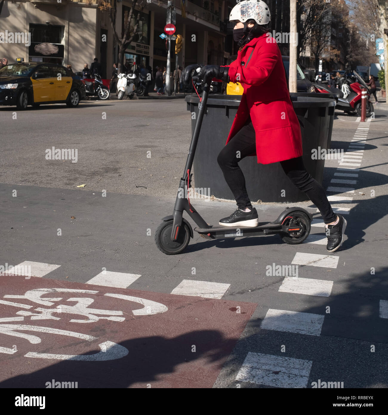 Frau, die einen elektroroller mit Helm um die Stadt herum, Barcelona, Spanien. Nachhaltige ökologische Mobilität. Stockfoto