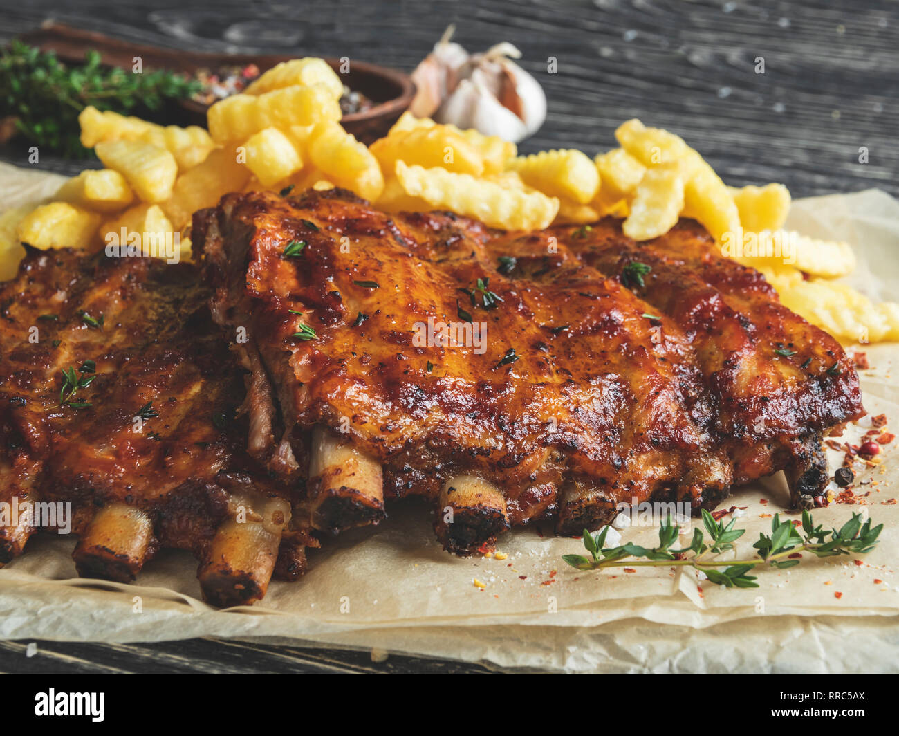 Gegrillte Schweinerippchen mit Sauce auf einem Schneidebrett, Pommes frites Stockfoto