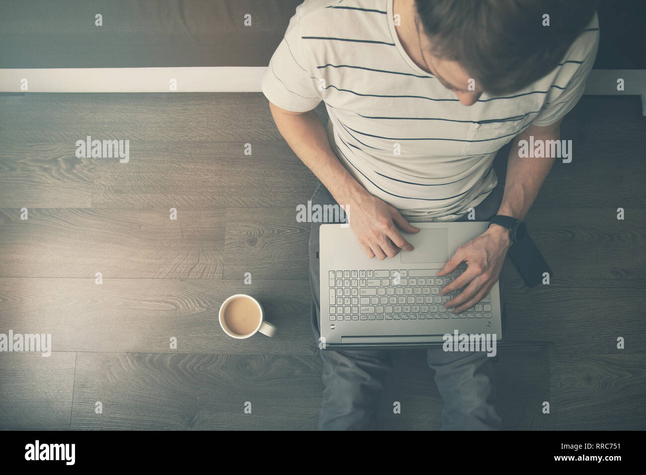Arbeiten von zu Hause - Mann sitzen auf dem Boden und mit Laptop Computer. top View Stockfoto