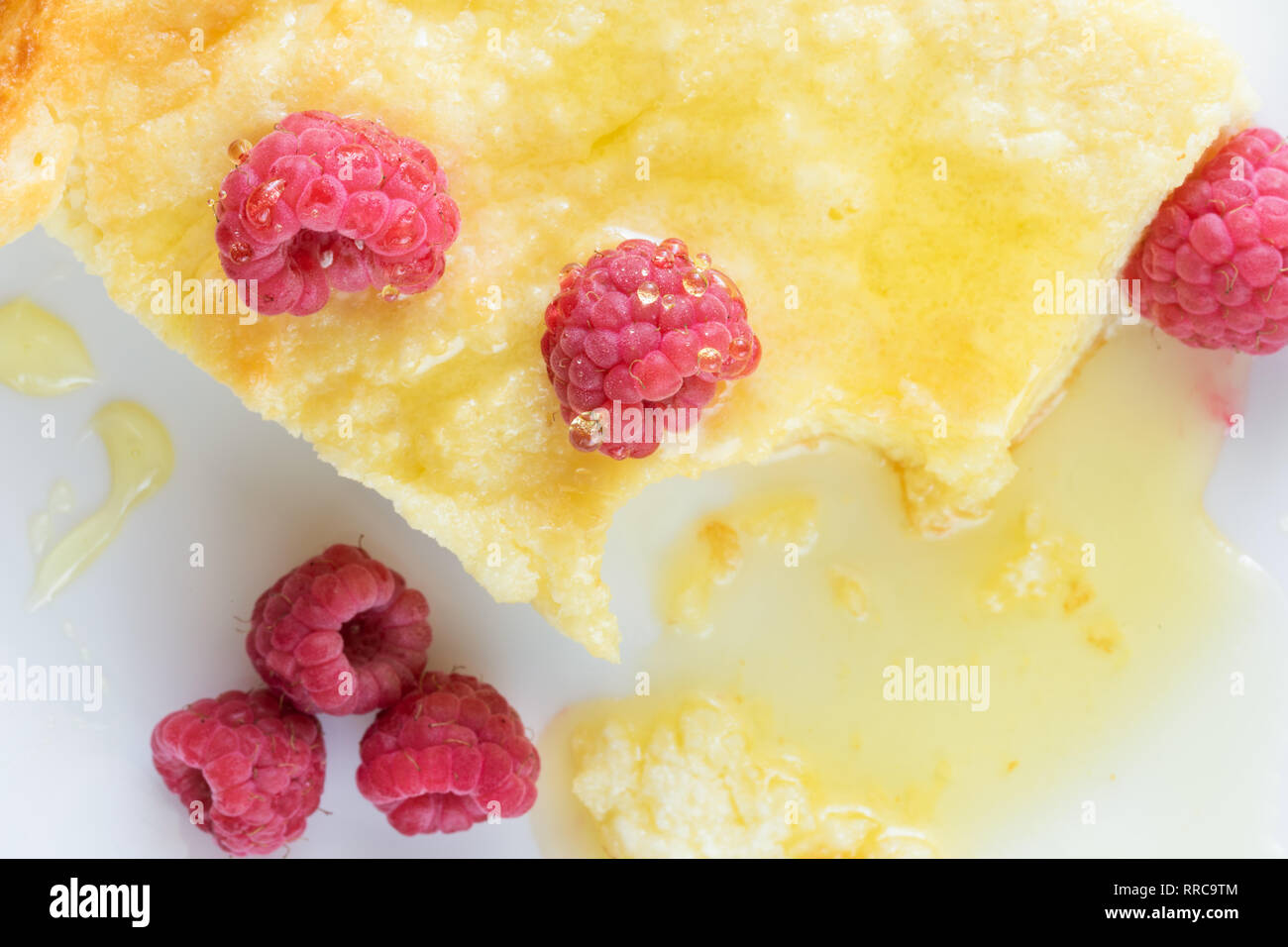 Close-up Stück der traditionellen Quark Auflauf mit Himbeeren und Honig auf weiße Platte. Stockfoto