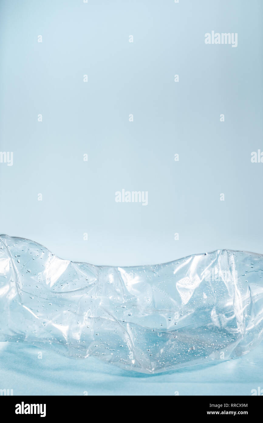 Kunststoffabfälle Konzept: verworfen zerknittert Wasserflasche in blauen Hintergrund. Details einer weggeworfenen single use Plastikflasche, die übermäßige Umfrage Stockfoto
