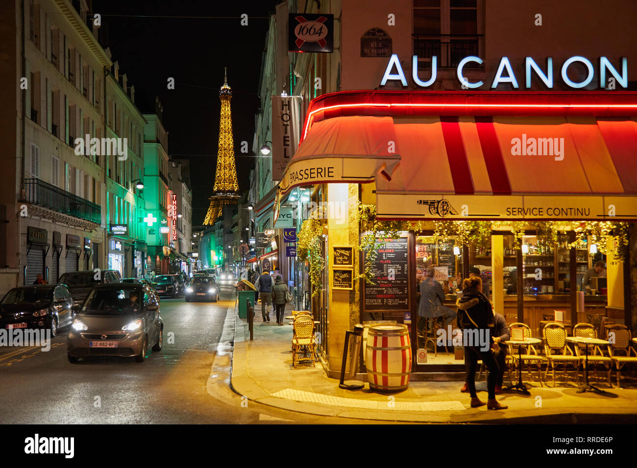PARIS - 8. NOVEMBER 2018: Eiffelturm bei Nacht und Straße beleuchtet mit Menschen und typischen Restaurant in Paris, Frankreich Stockfoto