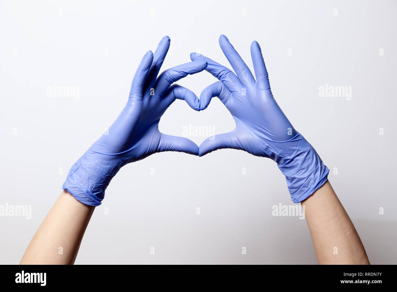 Nahaufnahme einer Hand in latex gummi Medizinische lila Handschuhe in ein  Herz Zeichen gefaltet. Auf weissem Hintergrund. Konzept Liebe Paar Paar  valentine Stockfotografie - Alamy