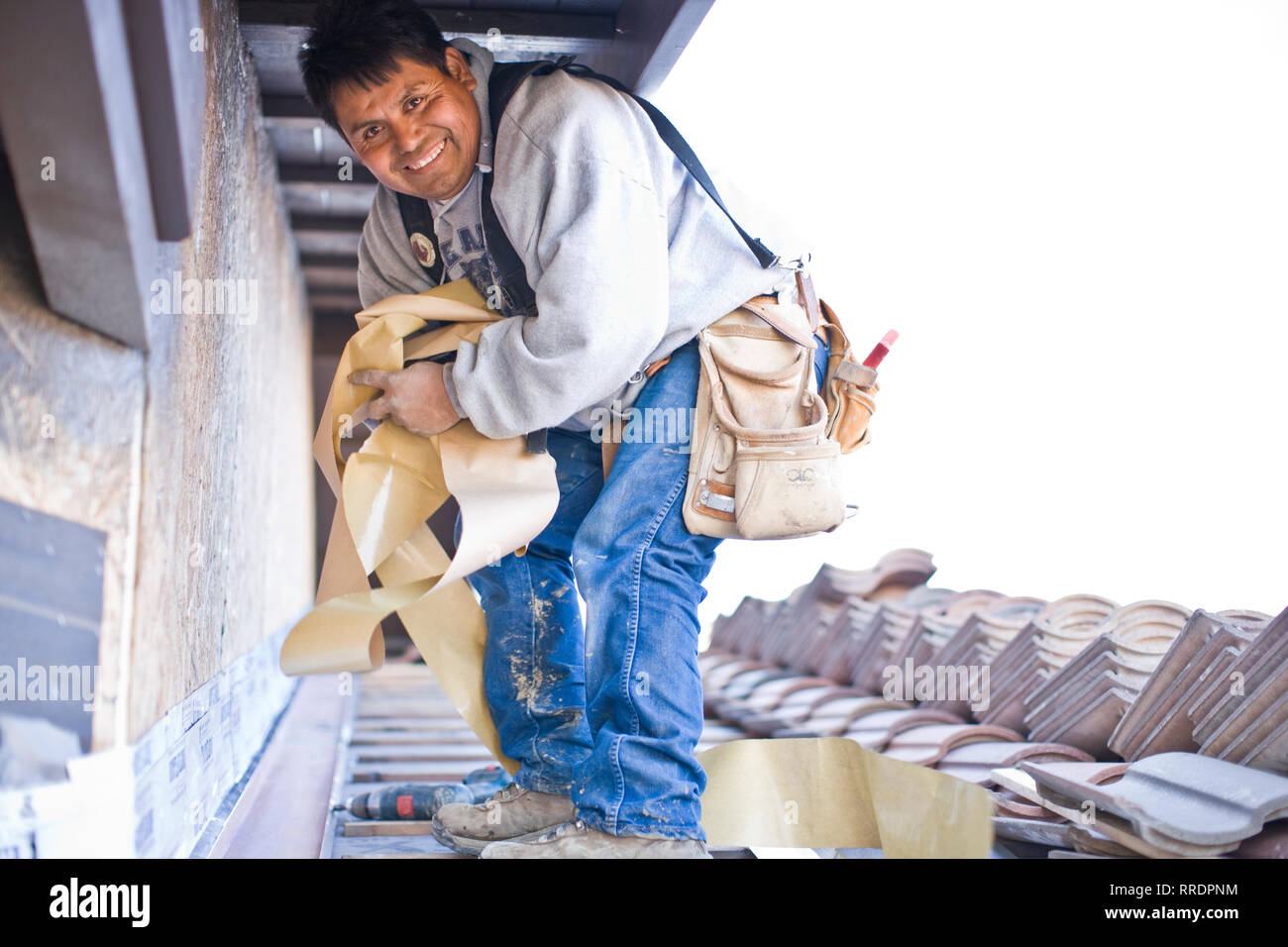 Porträt eines lächelnden Mann Tiling ein Dach. Stockfoto