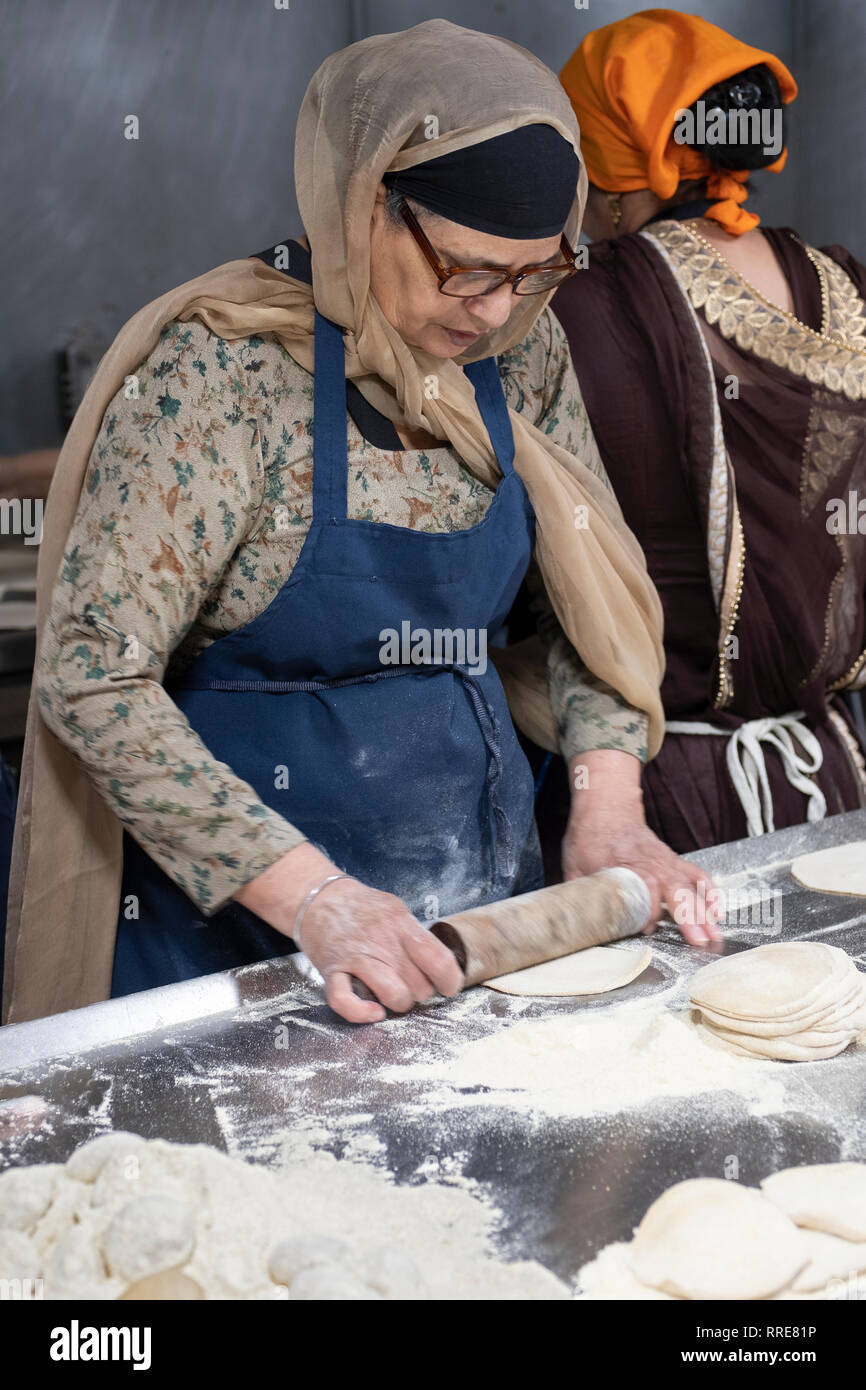 Eine Frau, die ehrenamtlich in einem langar, einem Sikh Tempel Küche, bereitet Roti, ein rundes dünnes Brot. In South Richmond Hill, Queens, New York City. Stockfoto