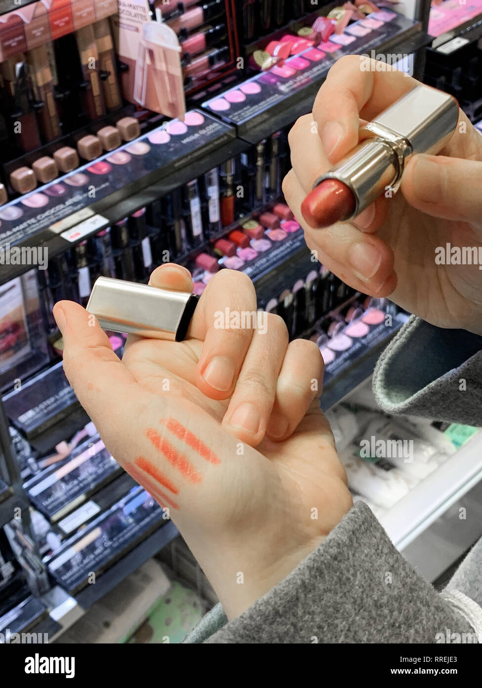 München, Deutschland - 27.Oktober 2018: die neugierige Frau kaufen in Kosmetik store roten Lippenstift liner zeichenstift zwischen der Vielzahl von unterschiedlichen Marken Stockfoto