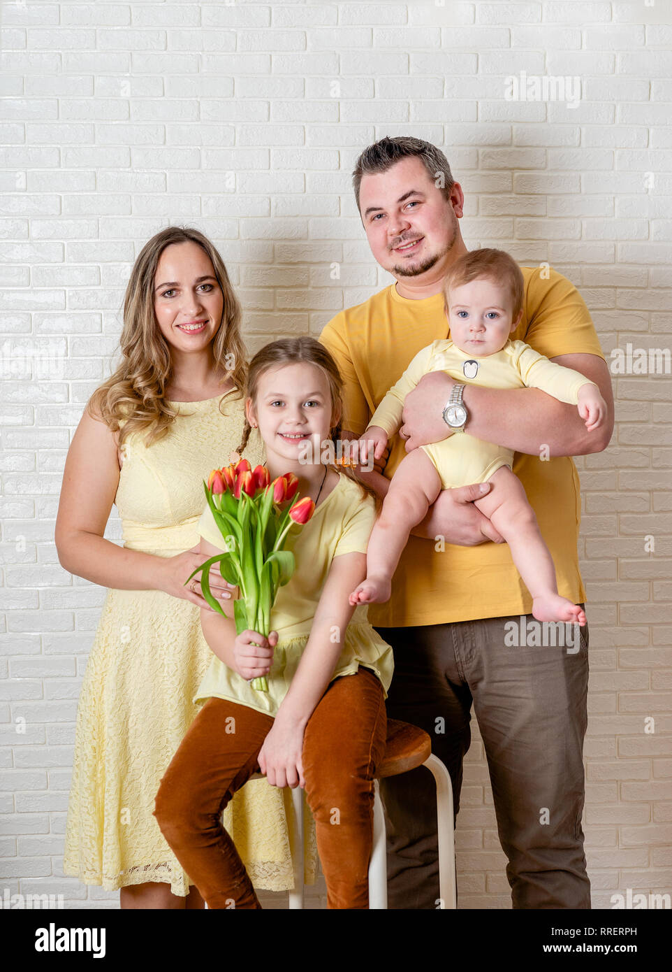 Funny Family Portrait auf Ostern von Mutter, Vater und Kinder tragen gelbe Kleidung und gegen weiße Wand posieren Stockfoto