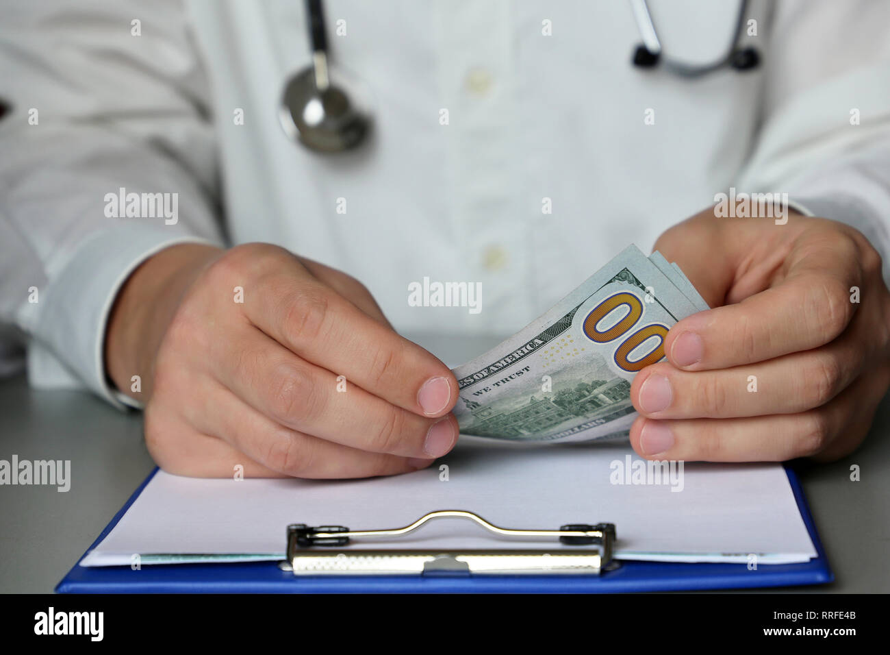 Arzt sitzen am Tisch mit Dollar in den Umschlag. Konzept für die Annahme von Bestechungsgeldern, Geld für medizinische Untersuchung, Bestechung, Korruption oder teure Healthcare Stockfoto