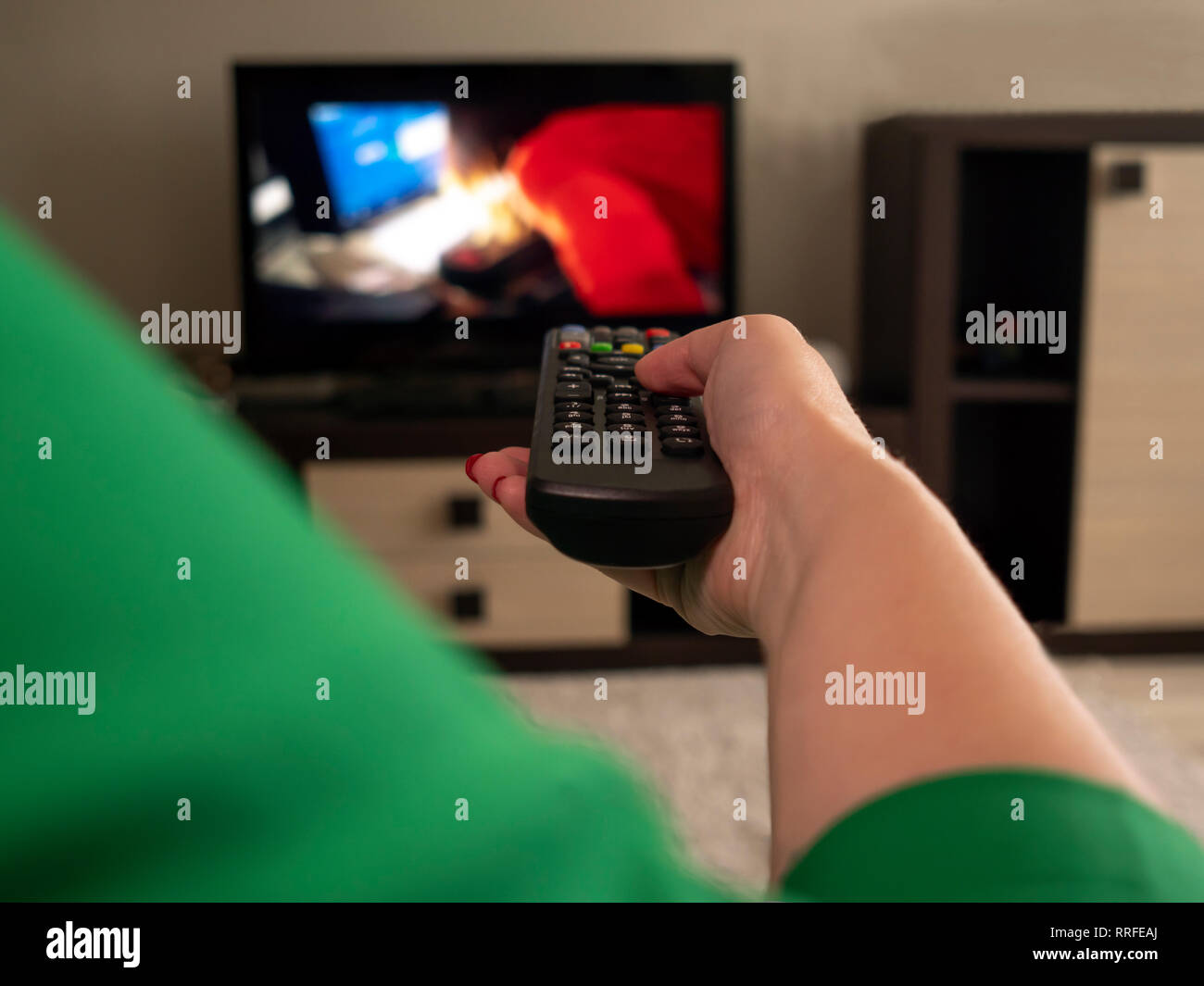 Weibliche Hand hält TV-Fernbedienung, Rückansicht Stockfoto