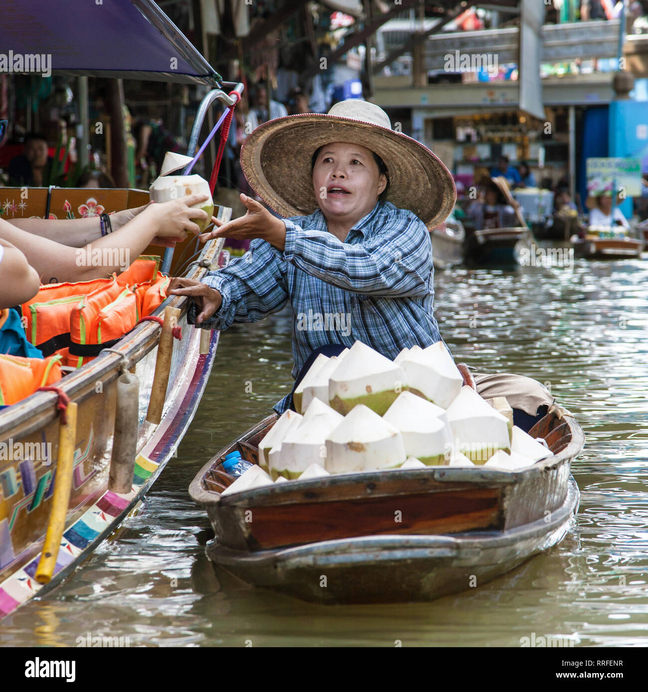 Damnoen Saduak, Thailand - 29. August 2018: Frau verkauft Kokosnüsse von einem Boot in Damnoen Saduak Markt, Ratchaburi, Thailand. Stockfoto