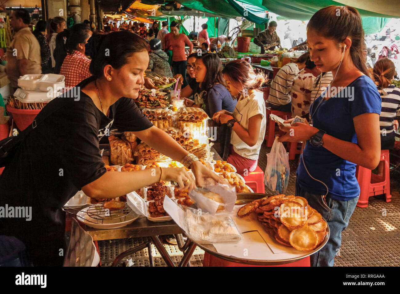 Mädchen mit Kopfhörern kauft das Essen im Speisesaal des riesigen Old Market, Central Market, Stadtzentrum, Phnom Penh, Kambodscha, Indochina Stockfoto