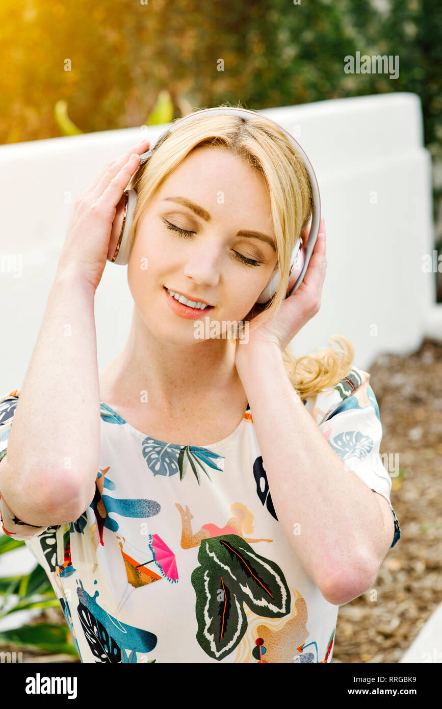 Junge hübsche Mädchen hört Musik auf Ihrem drahtlosen Kopfhörer Stockfoto