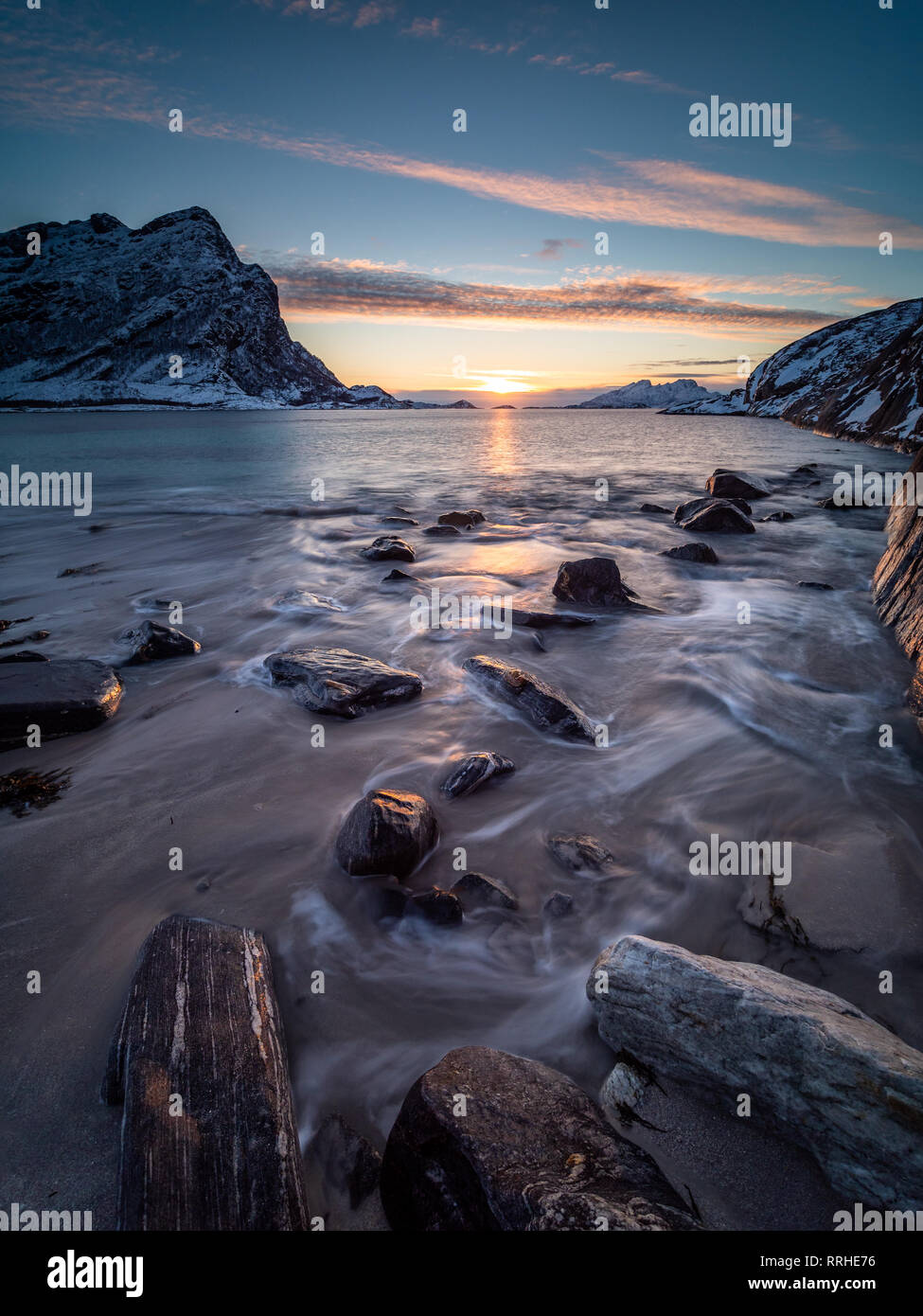 Sonnenuntergang vom Strand auf der Halbinsel Kjerringøy in Nord Norwegen mit der Bewegung der Wellen im Vordergrund gesehen. Stockfoto