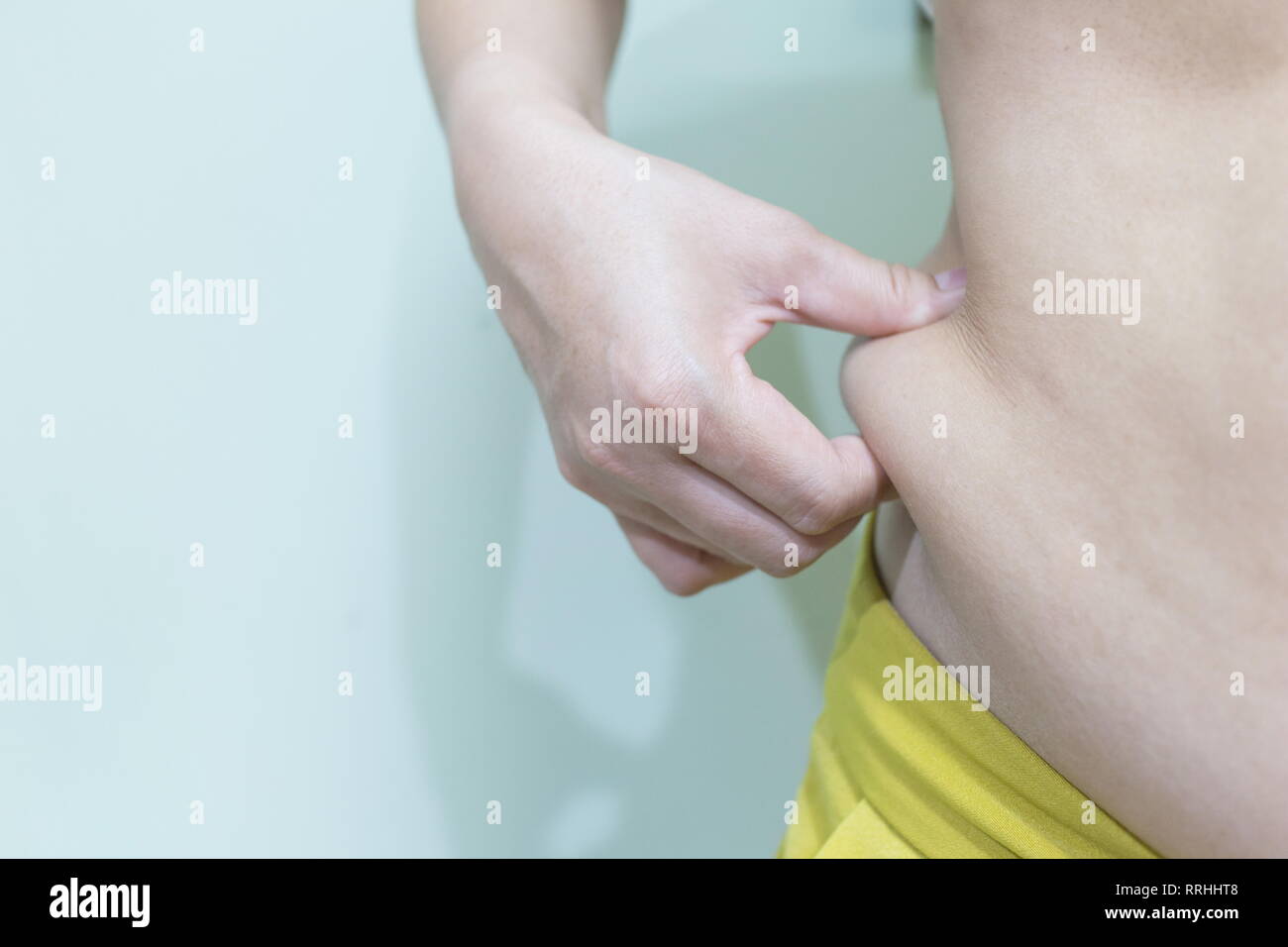 Woman's Hand hält eine Falte der überschüssiges Fett auf ihrem Bauch, Bild mit kopieren. Stockfoto