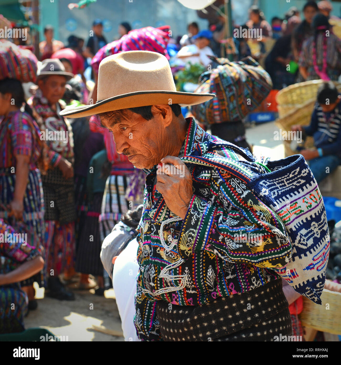 Das Porträt eines Mannes, der in traditioneller Kleidung auf dem Markt in Solola mit Maya Leute im Hintergrund Kauf und Verkauf von Waren, Guatemala. Stockfoto