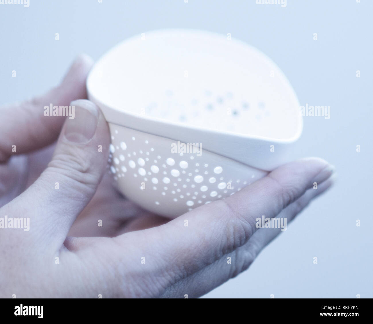 Hält eine Frau eine zerbrechliche Stück Keramik mit zwei Händen. Stockfoto