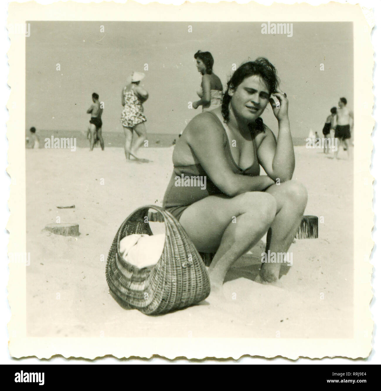 Deutschland. 1940er. Junge mollige Frau am Strand. In der Nähe des Korbs von korbmöbeln. Stockfoto