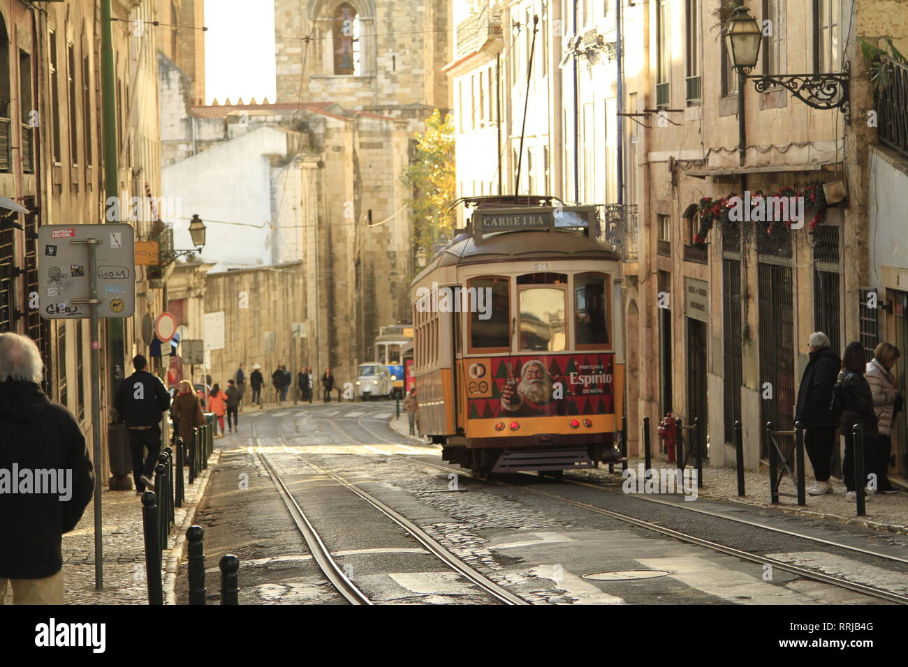 Gelbe Lissabonner Straßenbahn mit einem Turm der Se (Kathedrale) im Hintergrund, Alfama, Portugal Stockfoto