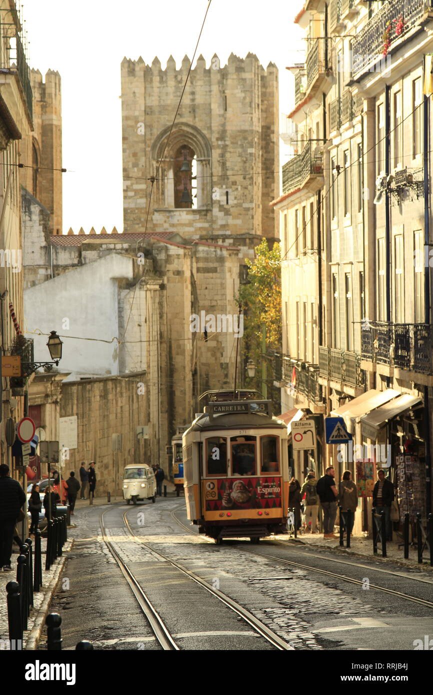 Gelbe Lissabonner Straßenbahn mit einem Turm der Se (Kathedrale) im Hintergrund, Alfama, Portugal Stockfoto