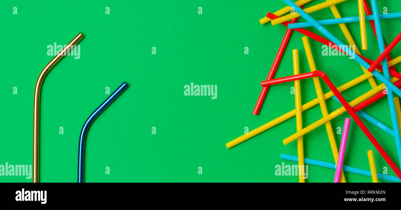 Zwei Edelstahl wiederverwendbare Trinkhalme mit viele bunte Plastik Strohhalme auf grünem Hintergrund. Kein Plastik, null Abfall Konzept Stockfoto