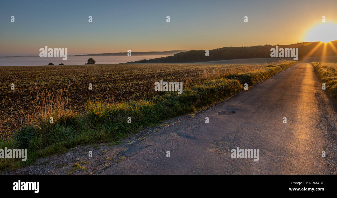 Schönen Nebel über Tal bei Sonnenaufgang und country lane mit Hügeln, knallen Stockfoto