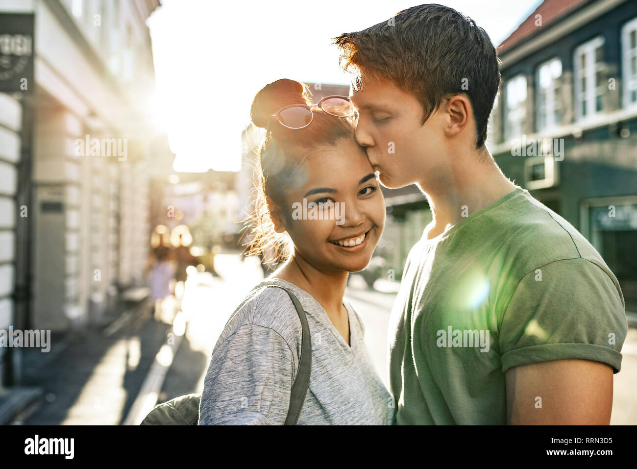 Junger Mann küssen Sein lächelndes Freundin auf einer Straße der Stadt Stockfoto