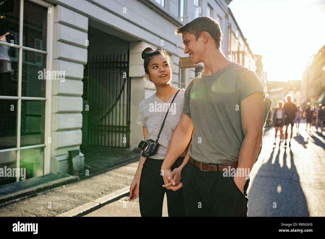 Lächelnde junge Paar erkunden Straßen der Stadt zusammen zu Fuß Stockfoto