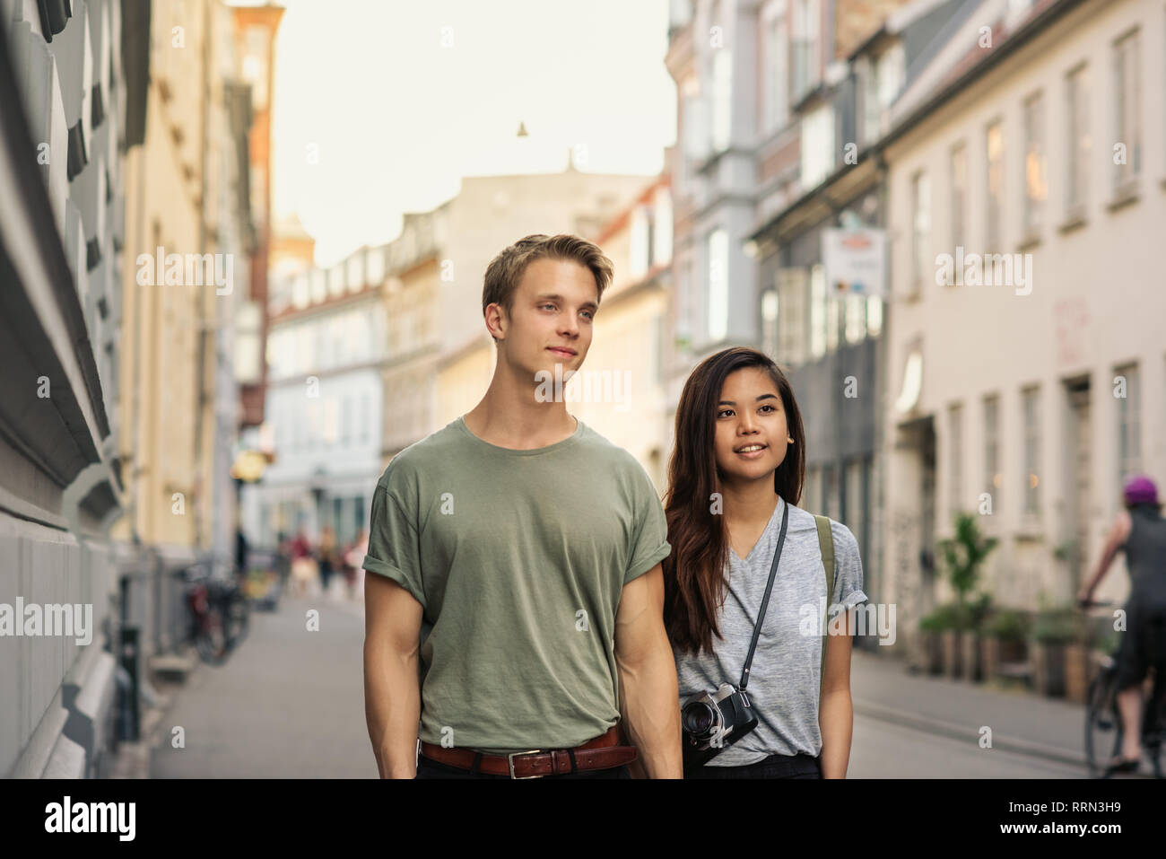 Lächelnden jungen Paar hält Hände beim Gehen in der Stadt Stockfoto