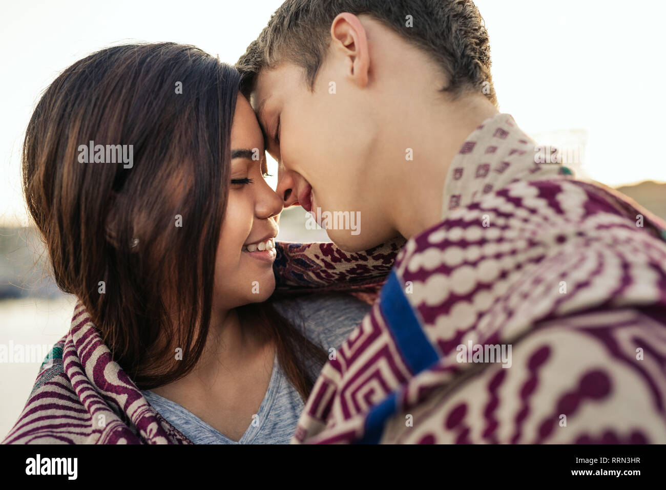 Junges Paar küssen, während in eine Decke eingewickelt zusammen außerhalb Stockfoto