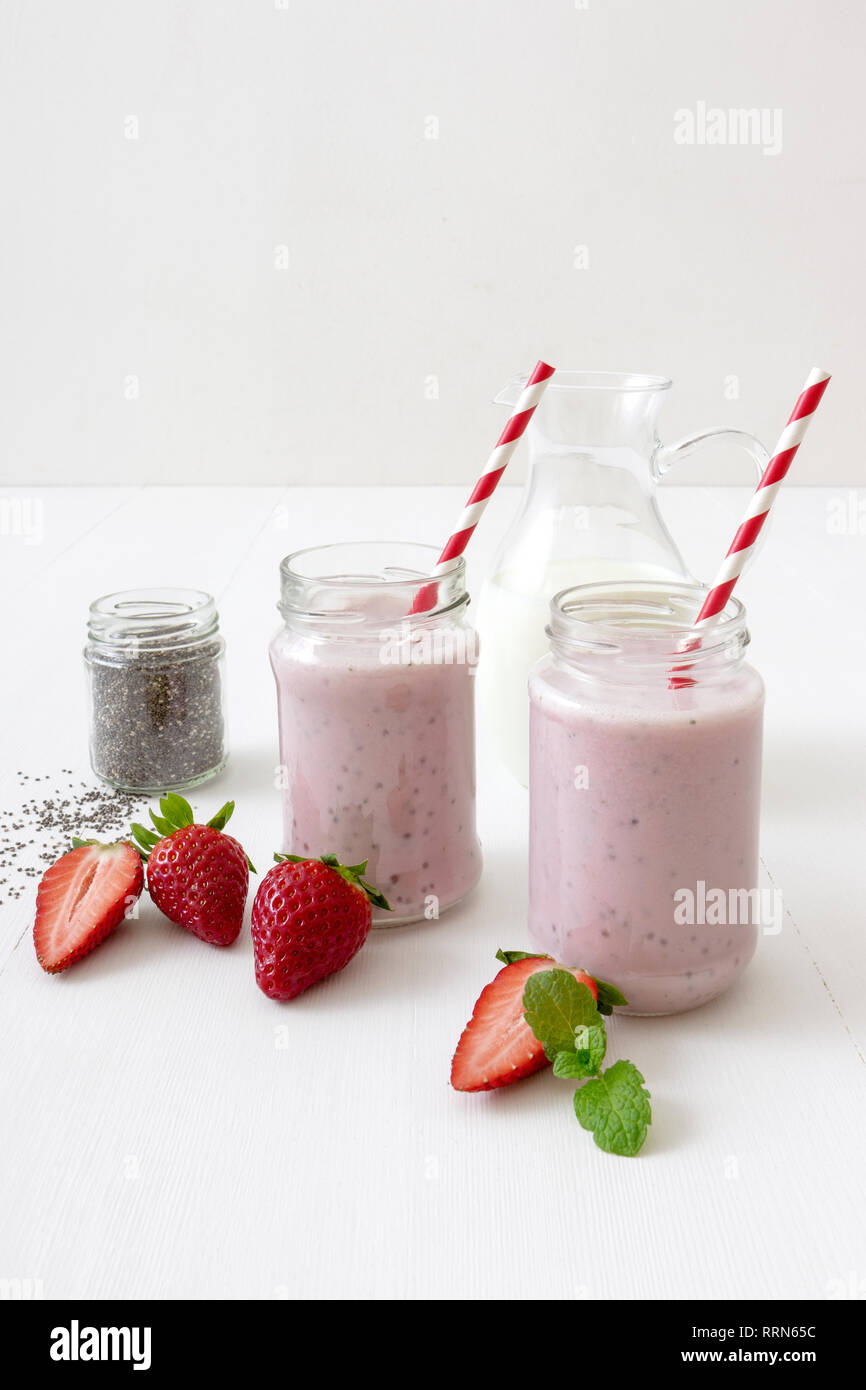 Strawberry Smoothie, Milchshake. 2 Gläser von erdbeermilch Smoothie und 1 Glas von Chia Samen auf weißen Tisch mit echten Erdbeeren verziert ein Stockfoto