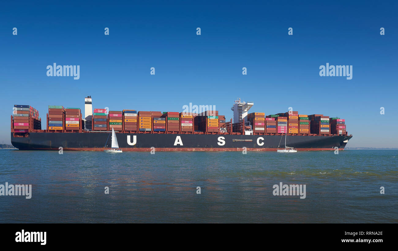 Zwei kleine Segelboote fahren in der Nähe des 400 Meter langen, ultragroßen Containerschiffs TIHAMA ab Southampton, UK, und auf dem Weg nach Le Havre, Frankreich. Stockfoto