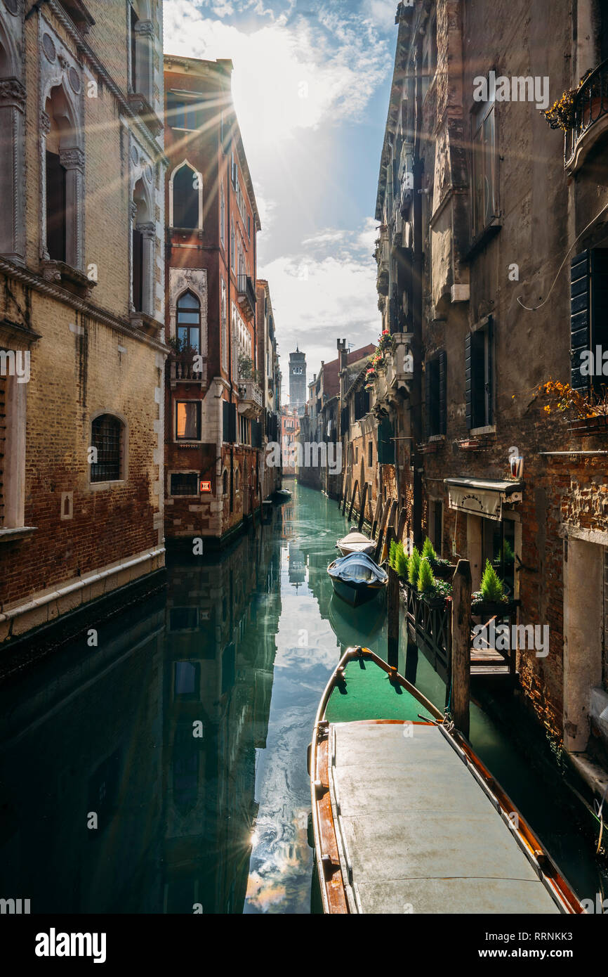 Sonne über ruhigen Gebäude und Kanal mit Gondeln, Venedig, Italien Stockfoto