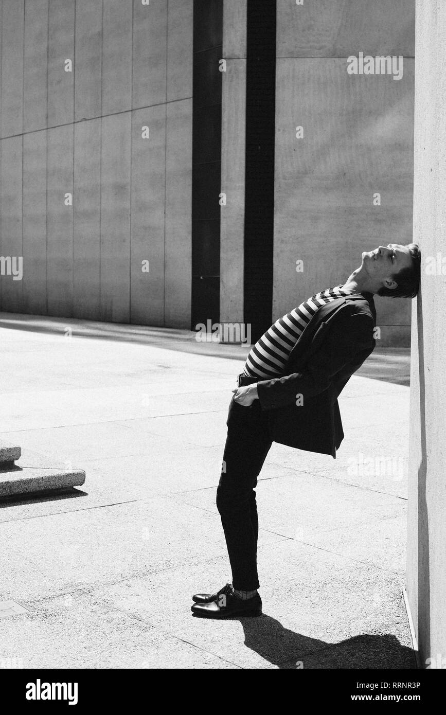 Mann im gestreiften Hemd schiefen Kopf gegen Wand Stockfoto