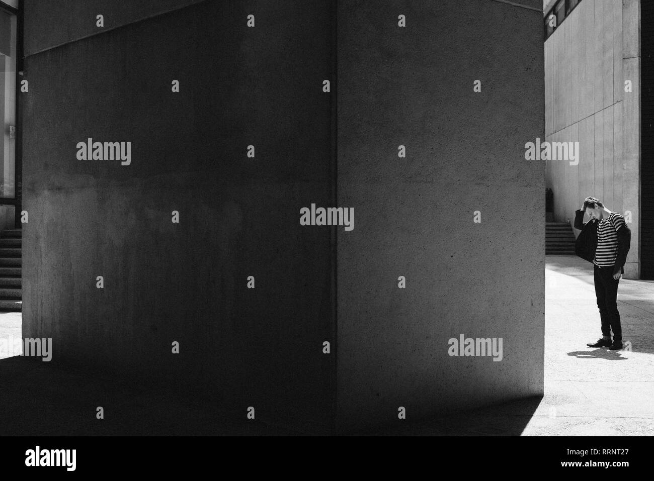 Coole jungen Mann mit der Hand im Haar ausserhalb städtischer Gebäude Stockfoto