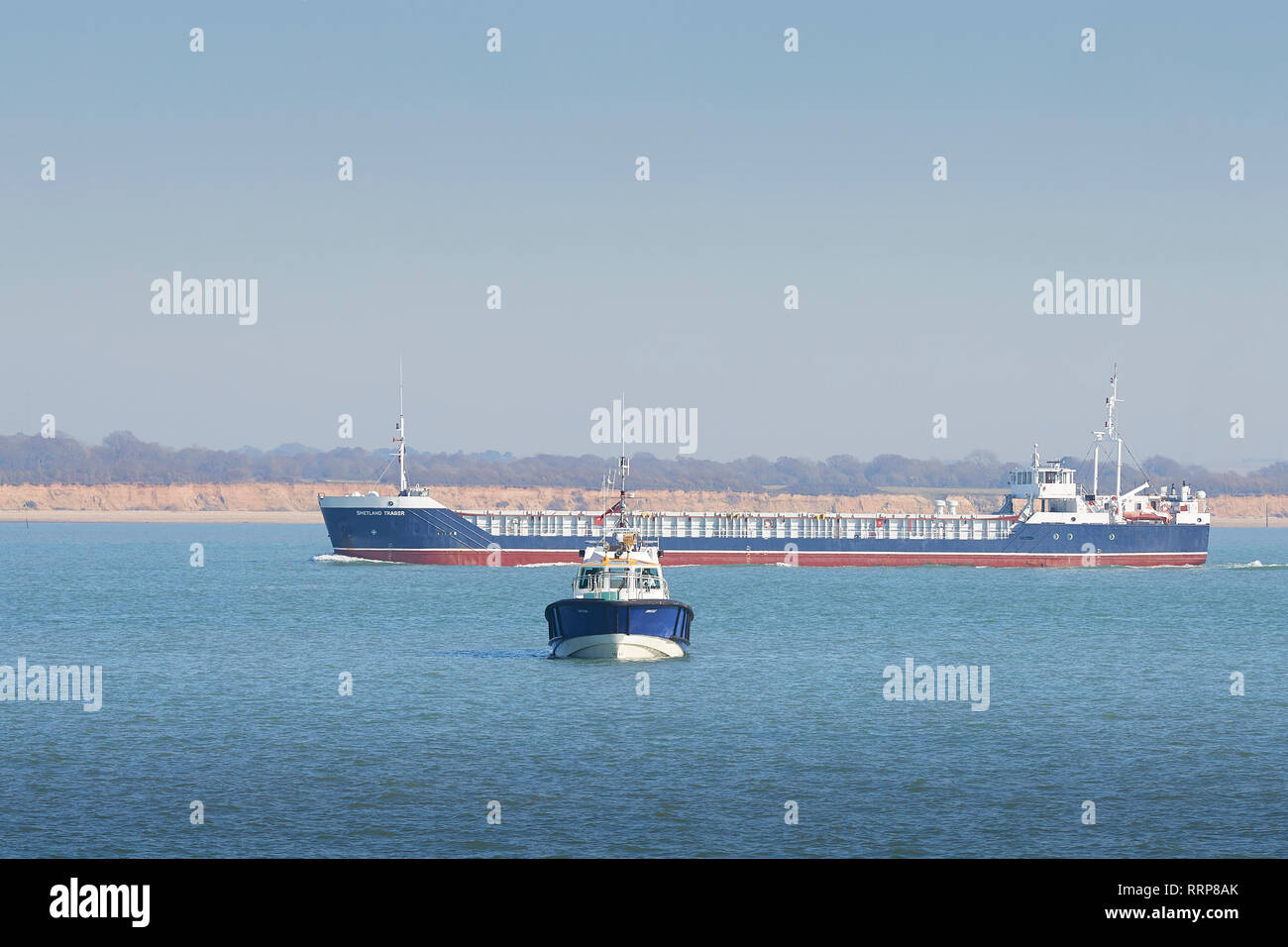 Gegen die Ansicht der Southampton Hafen Lotsenboot, Spitfire, wie der General Cargo Ship, SHETLAND TRADER, Pässe unterwegs, hinter sich. Southampton, Großbritannien. Stockfoto