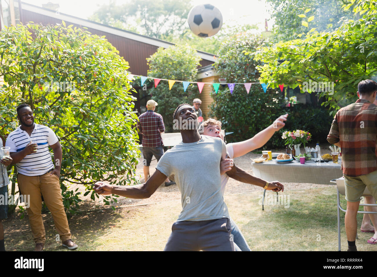 Männliche Freunde Fußball spielen, genießen Hinterhof Sommer Grill Stockfoto