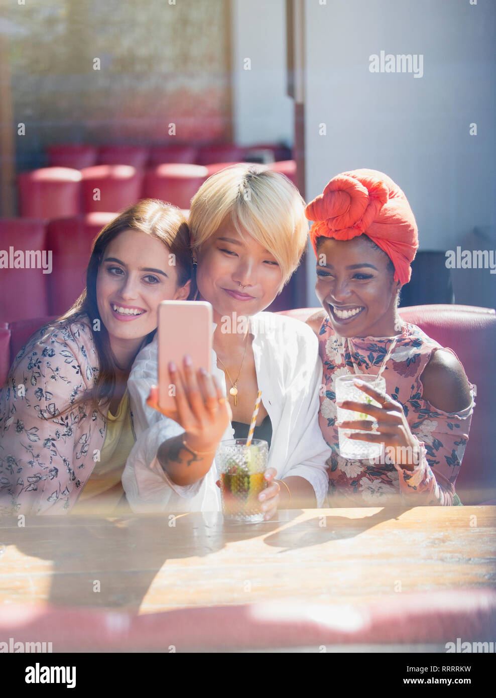 Junge Frauen, die Freunde trinken Cocktails und für selfie im sonnigen Restaurant posing Stockfoto