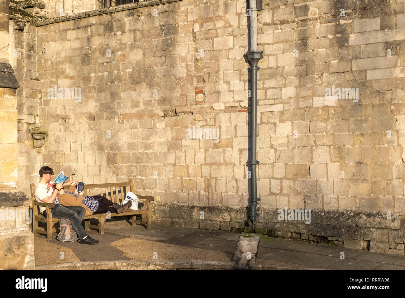 Buchliebhaber. Ein entspanntes Lesen in der Sonne, Winchester Cathedral, Winchester, Großbritannien Stockfoto