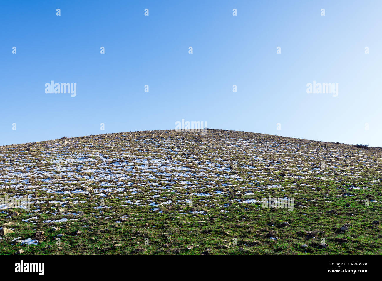Snowy alpine Hügel mit spärlichem Gras Stockfoto