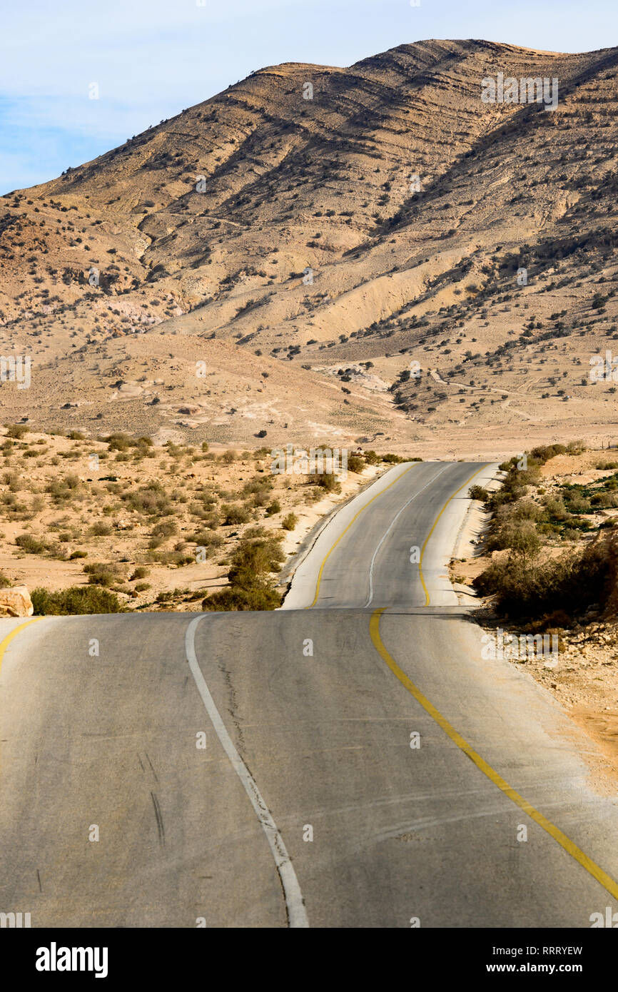Kings Highway, schöne kurvenreiche Straße durch das Wadi Rum Wüste mit Hügeln in der Ferne in Jordanien. Stockfoto
