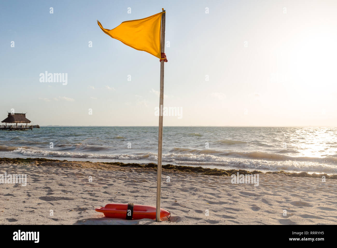 Eine gelbe Warnmeldung Markierung, die angibt, widrigen Bedingungen auf einer tropischen weißen Sandstrand. Stockfoto