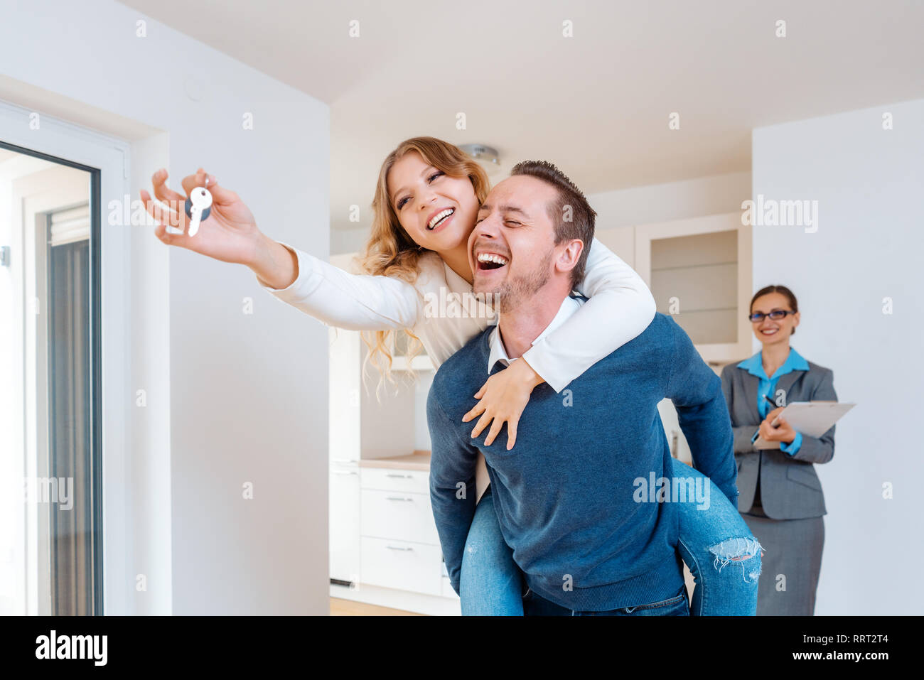 Mann, der seine Frau huckepack, zeigt das Haus Tasten Stockfoto