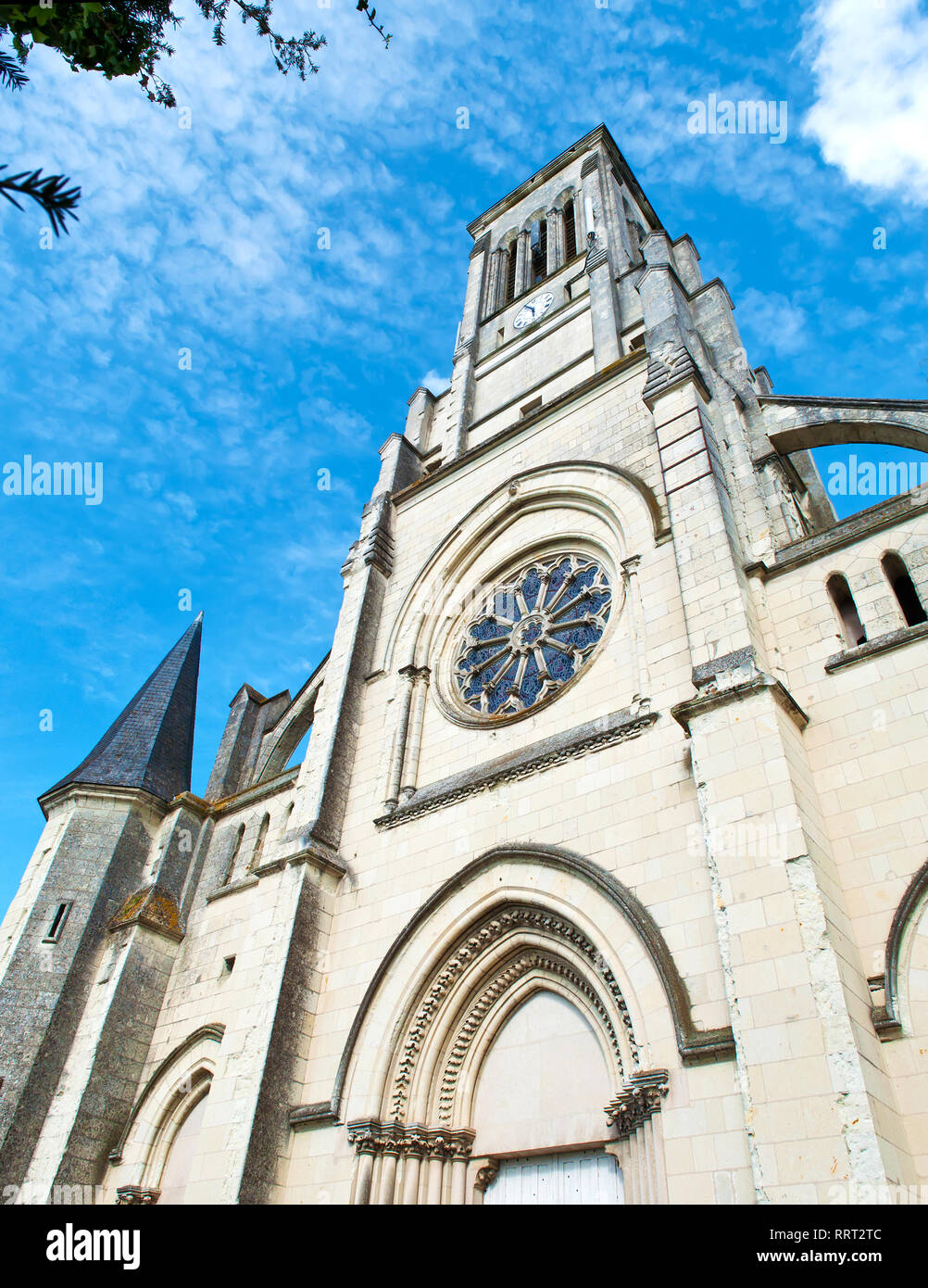 Architektonische Details der Eglise Kirche Saint-Symphorien in einer französischen Stadt La Pommeraye, Frankreich. Warmer Frühlingstag, vibrant blue sky mit dürren Wolken, gra Stockfoto