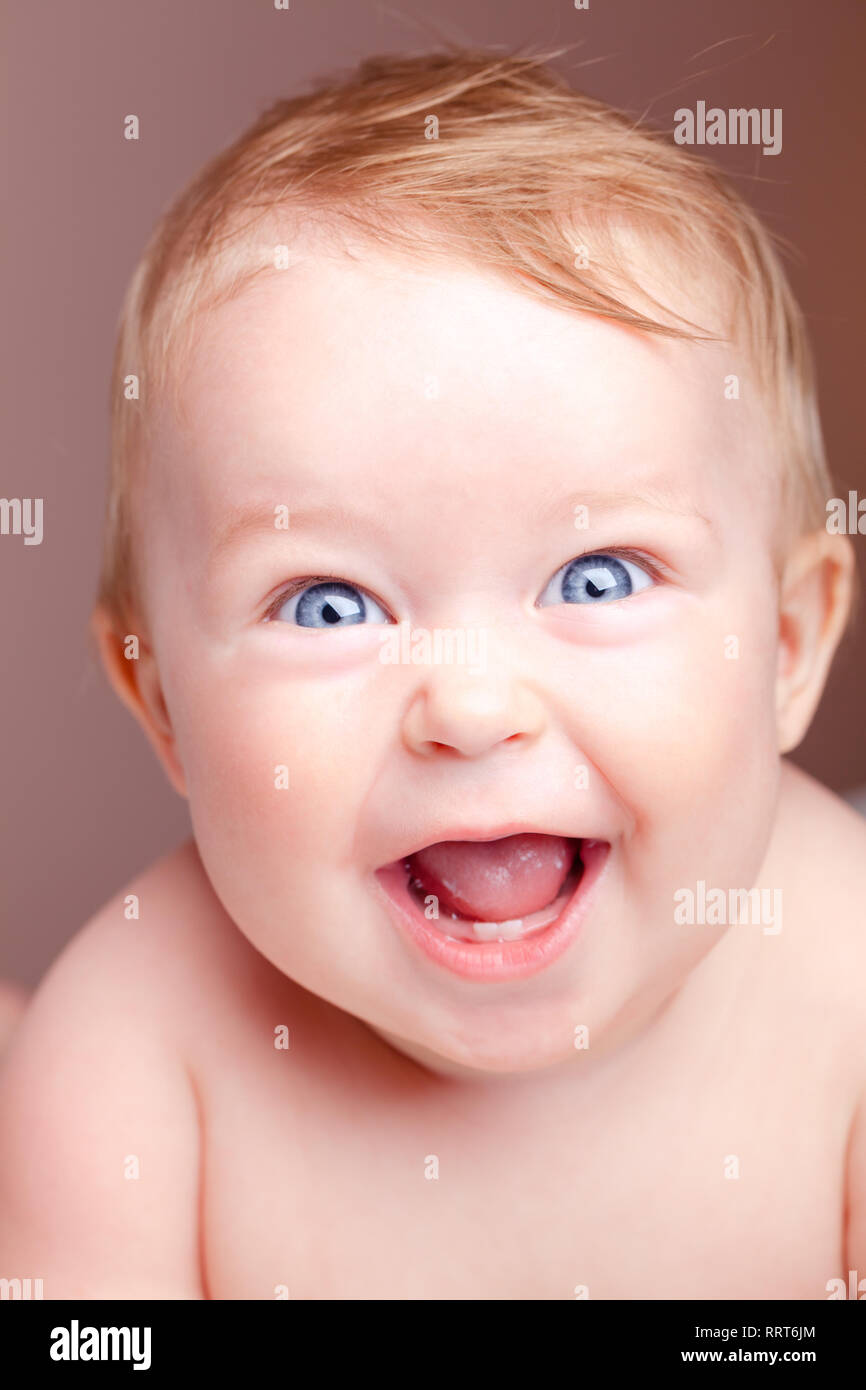 Kopf und Schultern Portrait von niedlichen blauen Augen Baby Mädchen auf Kamera und Lachen auf eine Koralle Farbe Hintergrund - glückliche Säugling oder Kindheit conc Stockfoto