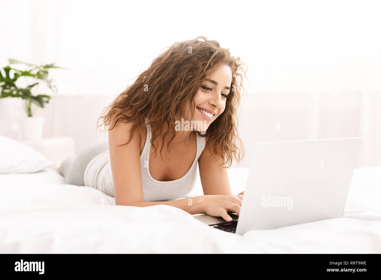 Glückliche Frau Flirten online auf Laptop im Bett Stockfoto